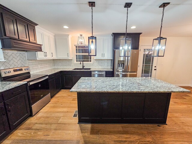 kitchen featuring stainless steel appliances, a center island, pendant lighting, and white cabinets