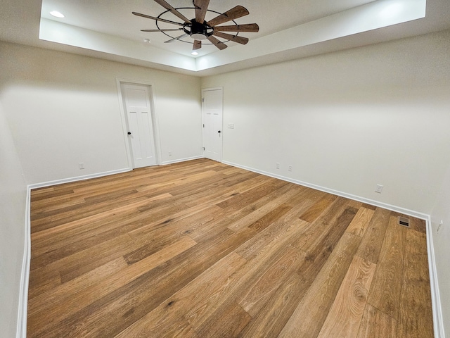 unfurnished room with a tray ceiling, wood-type flooring, and ceiling fan