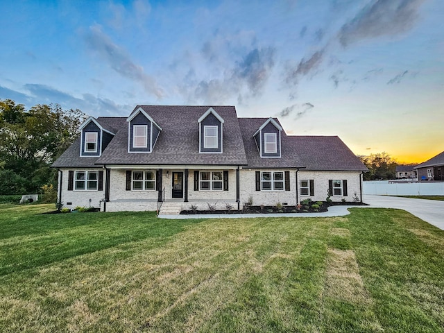 cape cod-style house featuring a lawn