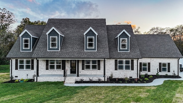 cape cod house featuring a lawn