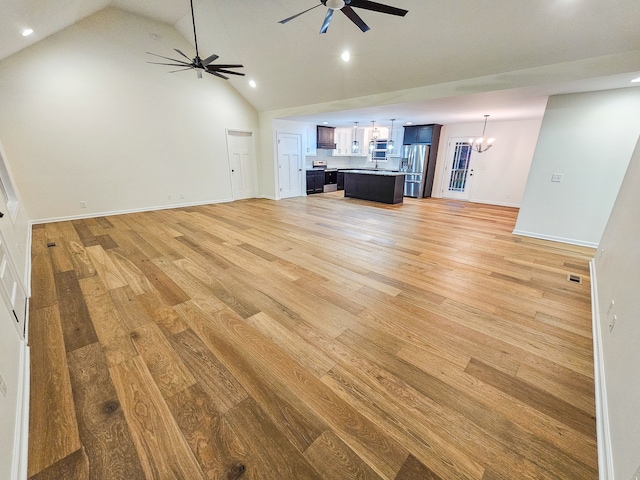 unfurnished living room with light hardwood / wood-style floors, high vaulted ceiling, and ceiling fan with notable chandelier