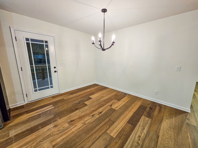 unfurnished dining area featuring a notable chandelier and dark hardwood / wood-style floors