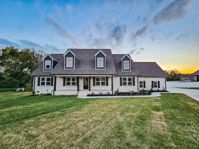 cape cod home with a lawn