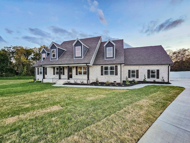 cape cod house with covered porch and a front yard