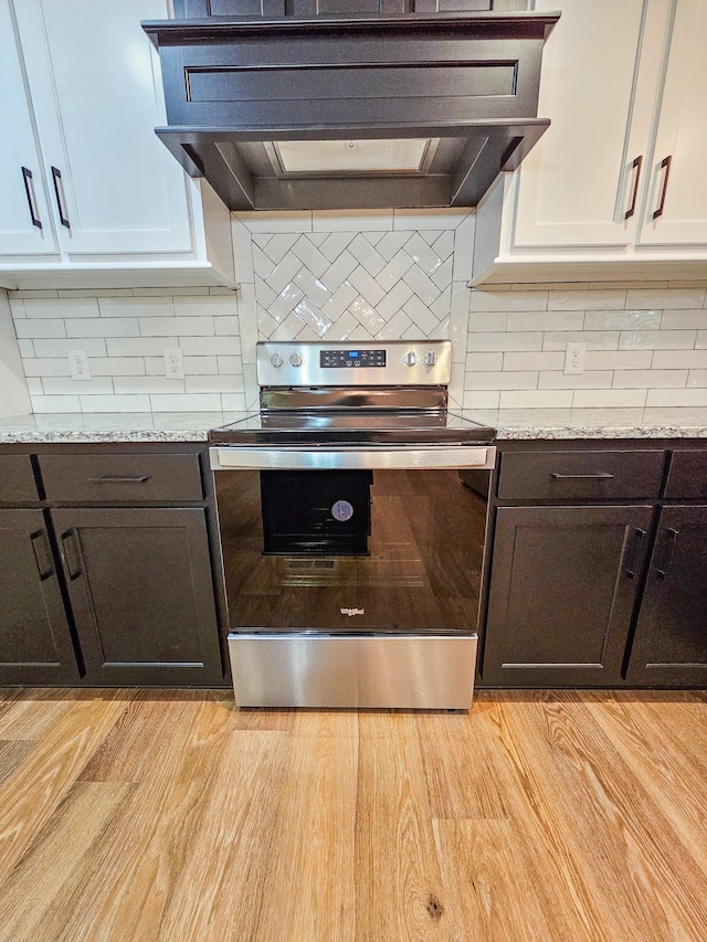 kitchen with electric range, premium range hood, white cabinetry, light hardwood / wood-style floors, and dark brown cabinetry