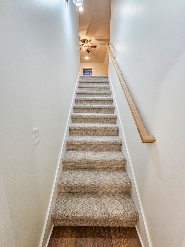 stairway with hardwood / wood-style floors and ceiling fan