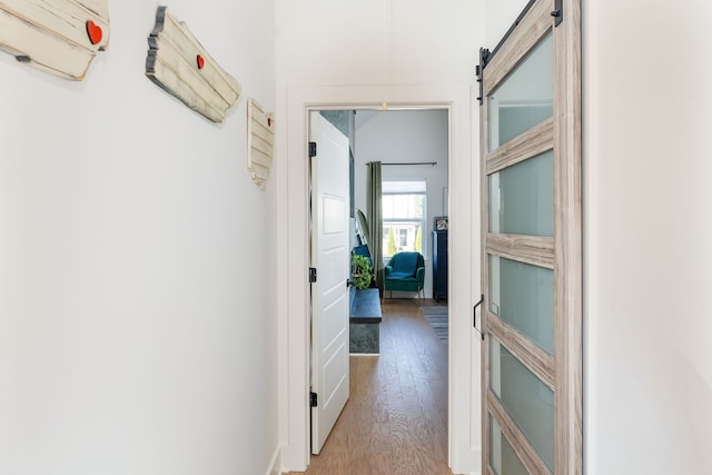 corridor featuring a barn door and light hardwood / wood-style flooring