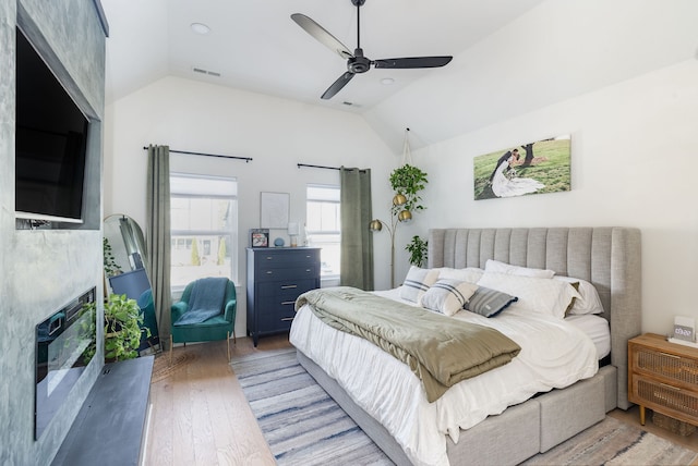 bedroom with ceiling fan, hardwood / wood-style floors, and vaulted ceiling