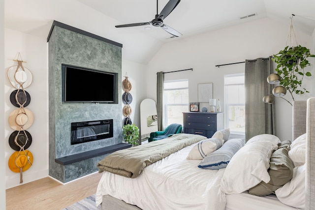 bedroom featuring a premium fireplace, ceiling fan, light hardwood / wood-style floors, and lofted ceiling