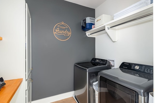 laundry room with washer and dryer and wood-type flooring