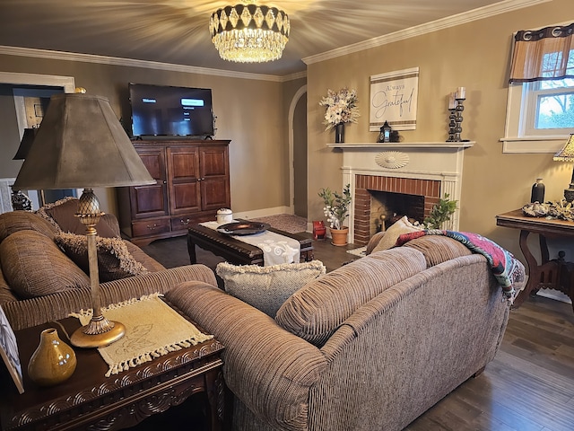 living room featuring dark wood-type flooring, ornamental molding, a chandelier, and a fireplace