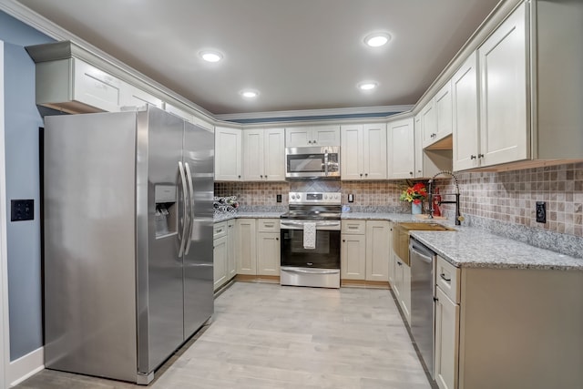 kitchen with light stone countertops, sink, stainless steel appliances, decorative backsplash, and light hardwood / wood-style flooring