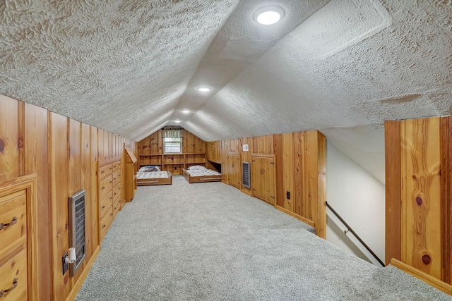 additional living space with a textured ceiling, wood walls, light colored carpet, and vaulted ceiling