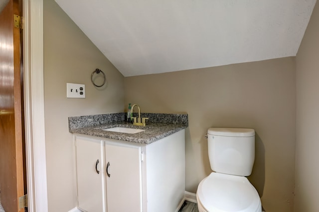 bathroom featuring vanity, lofted ceiling, and toilet