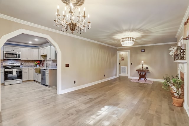 kitchen with backsplash, white cabinetry, light hardwood / wood-style floors, crown molding, and stainless steel appliances