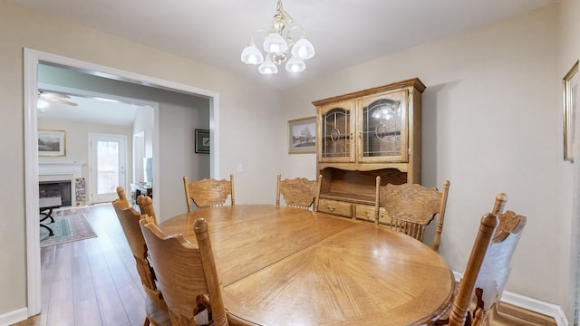 dining room featuring ceiling fan with notable chandelier and hardwood / wood-style flooring