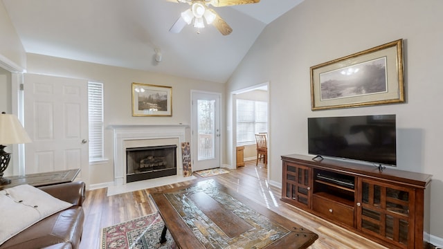 living room with ceiling fan, light hardwood / wood-style floors, and lofted ceiling