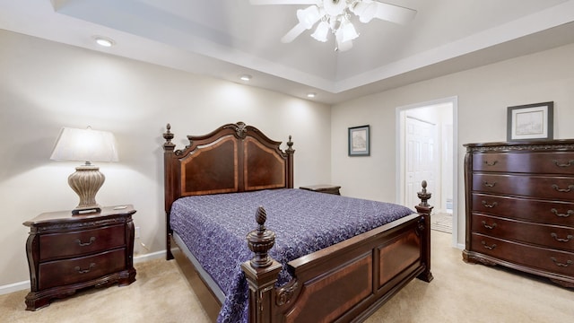 carpeted bedroom with a tray ceiling and ceiling fan