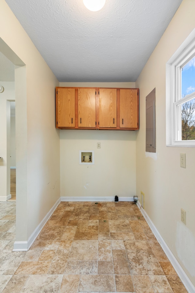 clothes washing area with a textured ceiling, hookup for a washing machine, and cabinets