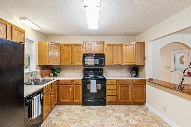 kitchen with a textured ceiling, sink, black appliances, and decorative backsplash