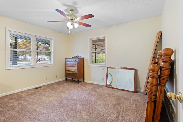 bedroom featuring ceiling fan, a textured ceiling, and light carpet