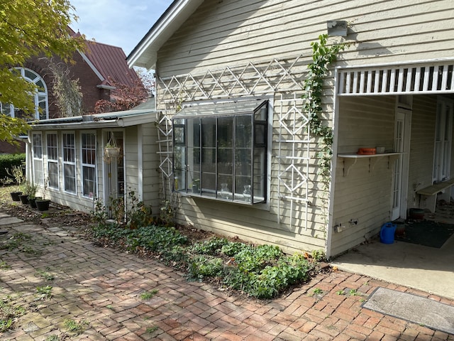 view of property exterior with a sunroom and a patio area