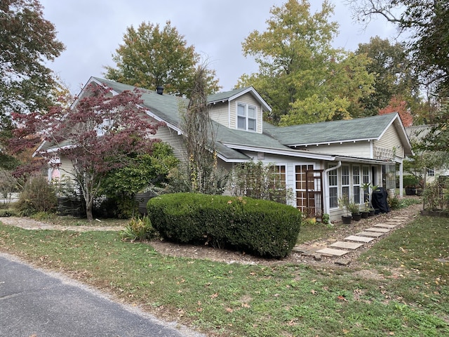 view of side of property with a sunroom and a yard