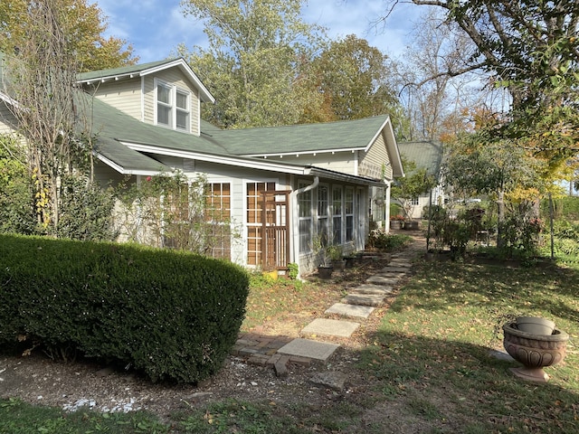 view of property exterior featuring a sunroom and a yard