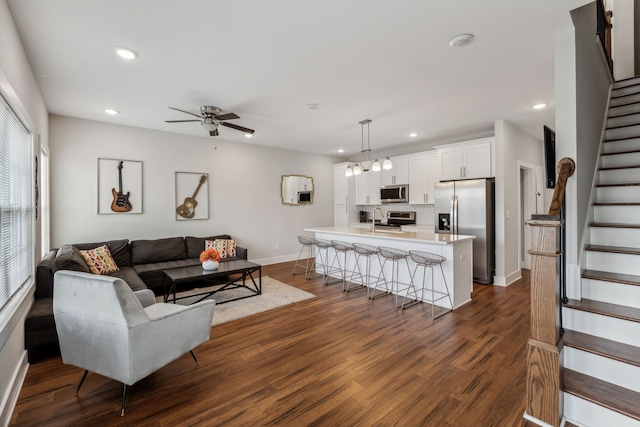 living room with sink, dark wood-type flooring, and ceiling fan