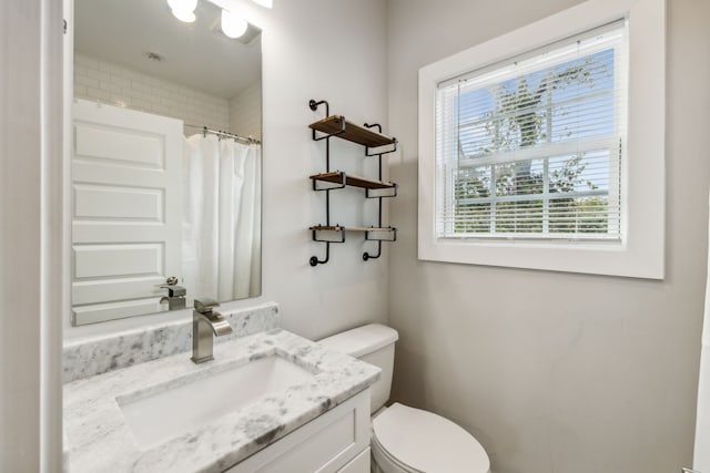 bathroom featuring a healthy amount of sunlight, vanity, a shower with curtain, and toilet