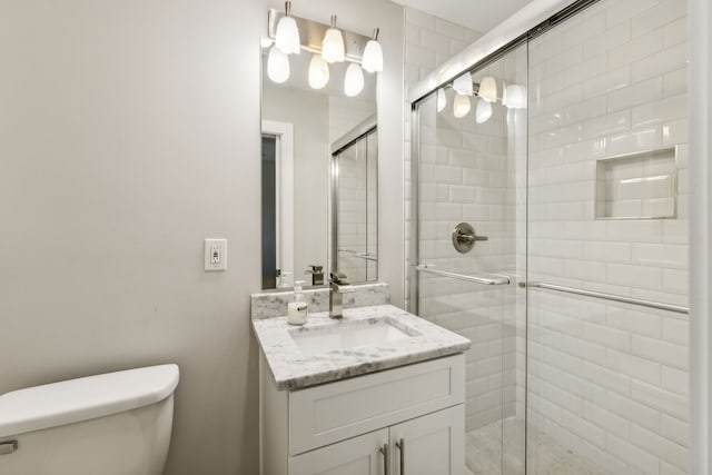 bathroom with vanity, toilet, and a shower with shower door