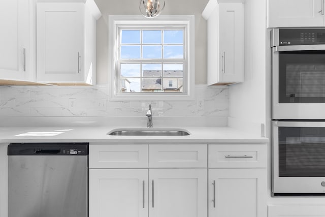 kitchen with white cabinetry, stainless steel appliances, sink, and backsplash