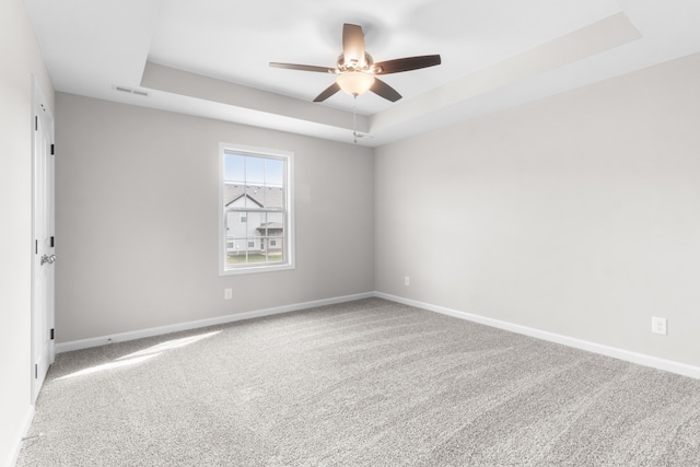 carpeted empty room with a tray ceiling and ceiling fan