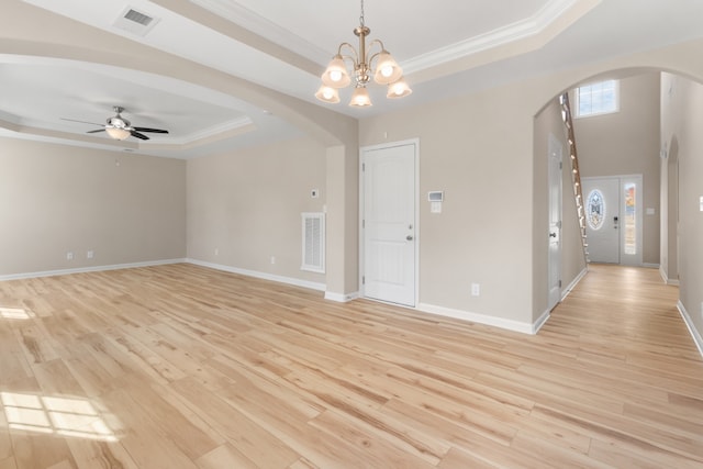 spare room featuring light hardwood / wood-style floors, crown molding, a tray ceiling, and ceiling fan with notable chandelier