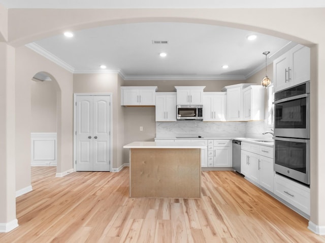 646 Woodrush Dr, Clarksville, TN 37040 - kitchen featuring stainless steel appliances, arched walkways, a kitchen island, a sink, and light wood finished floors