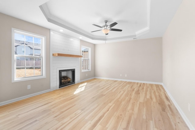 646 Woodrush Dr, Clarksville, TN 37040 - unfurnished living room with a tray ceiling, light wood-style flooring, ceiling fan, a fireplace, and baseboards