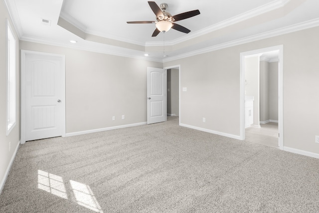 carpeted empty room with ornamental molding, ceiling fan, and a raised ceiling