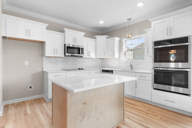 kitchen with a center island, appliances with stainless steel finishes, white cabinetry, and light hardwood / wood-style floors