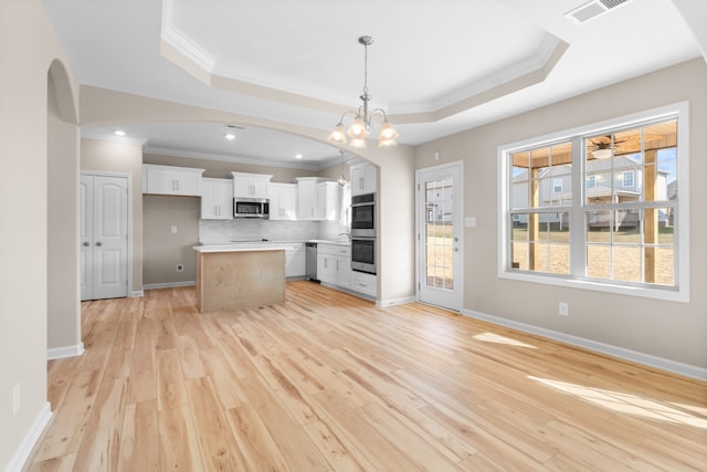 kitchen featuring stainless steel appliances, a center island, decorative light fixtures, light wood-type flooring, and white cabinets