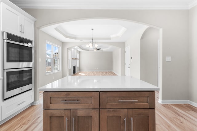 kitchen featuring white cabinetry, double oven, light wood-type flooring, and an inviting chandelier