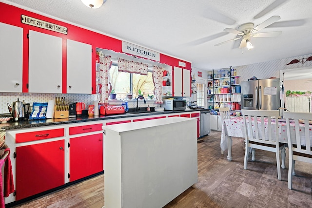 kitchen with a kitchen island, hardwood / wood-style flooring, stainless steel appliances, sink, and ceiling fan