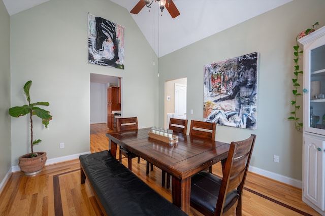 dining area with ceiling fan, high vaulted ceiling, and light hardwood / wood-style flooring