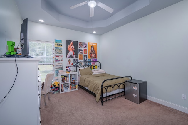 carpeted bedroom with ceiling fan and a raised ceiling