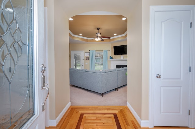 entrance foyer with ceiling fan, hardwood / wood-style flooring, ornamental molding, and a tray ceiling