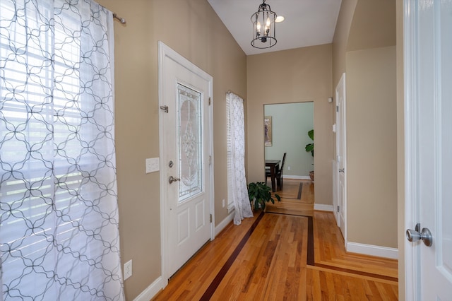 foyer entrance with hardwood / wood-style floors and a notable chandelier