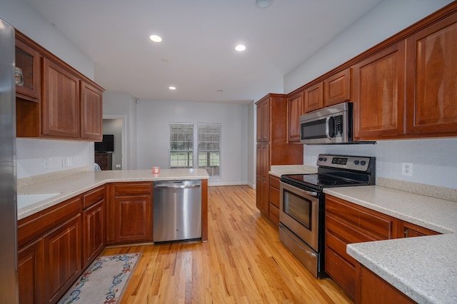 kitchen with light hardwood / wood-style floors, stainless steel appliances, and kitchen peninsula