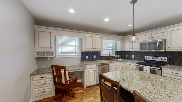 kitchen featuring tasteful backsplash, appliances with stainless steel finishes, sink, light wood-type flooring, and hanging light fixtures