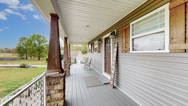 wooden terrace featuring a yard and covered porch