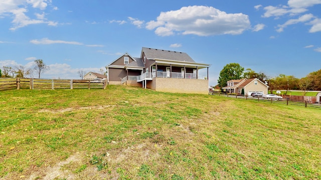 rear view of house with a yard, a balcony, and a rural view