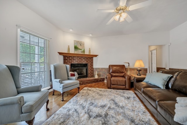 living room featuring ceiling fan, light hardwood / wood-style flooring, and a fireplace